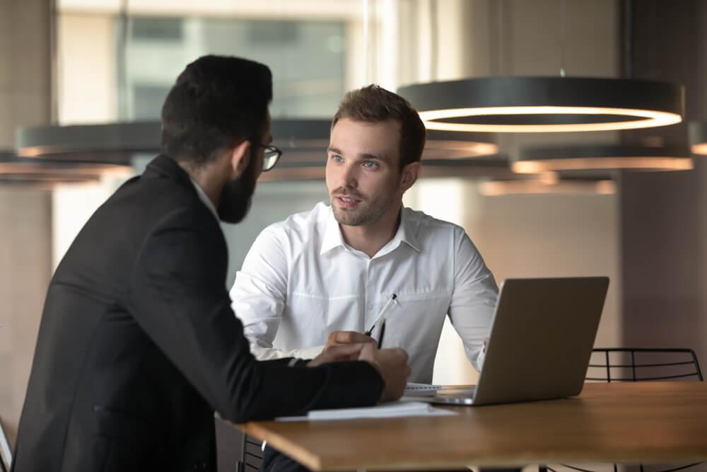 Young multiracial businessmen talk sharing considering business idea or project working on laptop in office.